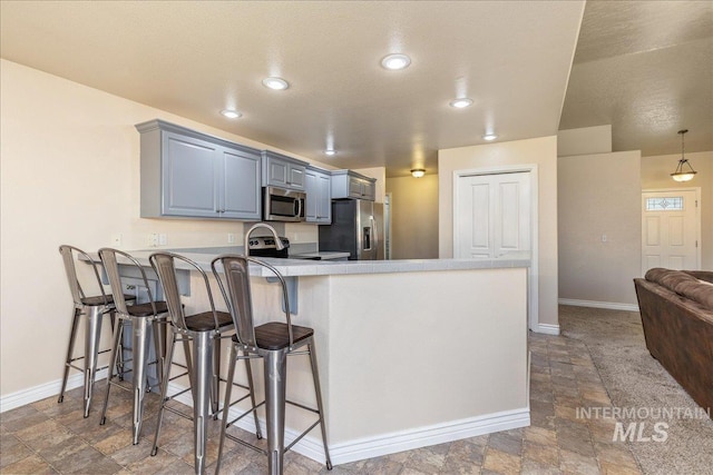 6229 S Snowdrop Way, Boise, ID 83716 - kitchen with stainless steel appliances, a peninsula, stone finish flooring, baseboards, and a breakfast bar area