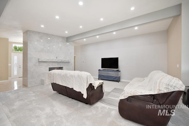 living room featuring a tiled fireplace and beamed ceiling