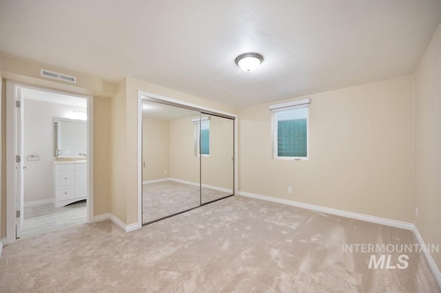 unfurnished bedroom with light carpet and a closet