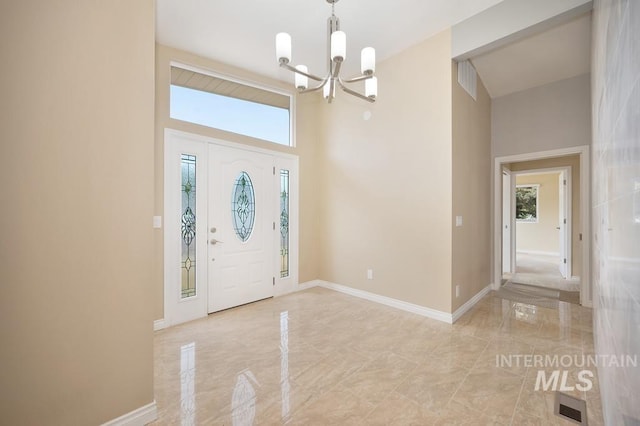 foyer featuring an inviting chandelier, a towering ceiling, and a wealth of natural light