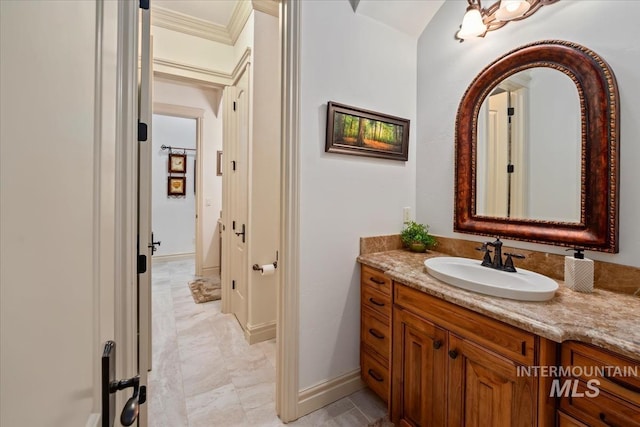 bathroom with vanity, ornamental molding, and baseboards