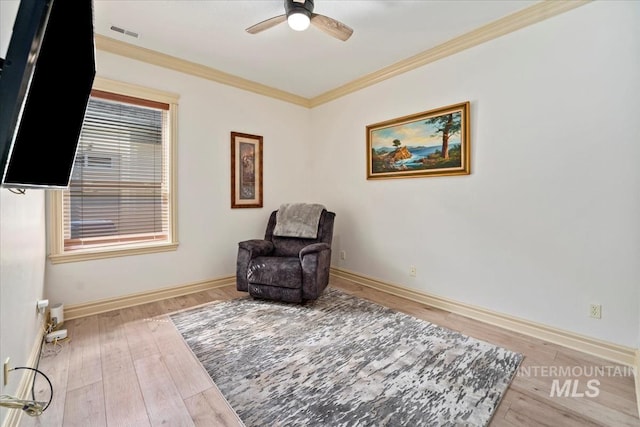 sitting room featuring crown molding, a ceiling fan, baseboards, wood finished floors, and visible vents