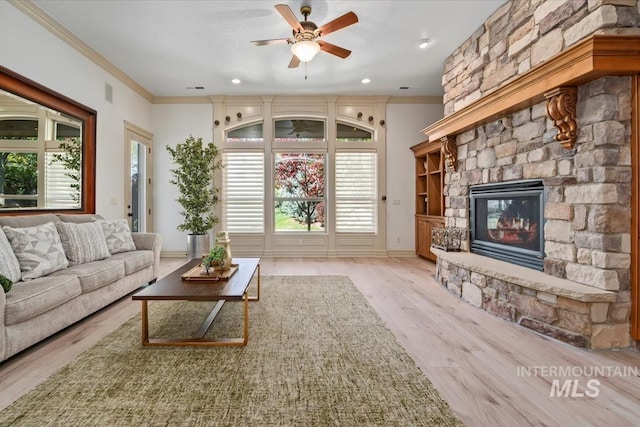 living room featuring crown molding, ceiling fan, a fireplace, and wood finished floors