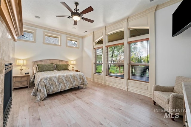 bedroom featuring crown molding, ceiling fan, and light wood-style flooring