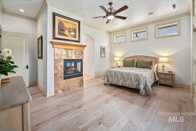 bedroom featuring crown molding, arched walkways, and light wood finished floors