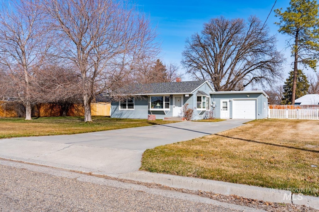 ranch-style home with fence, concrete driveway, an attached garage, a front yard, and a chimney