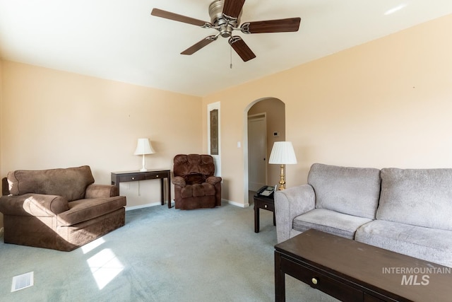 living area with visible vents, ceiling fan, baseboards, carpet, and arched walkways