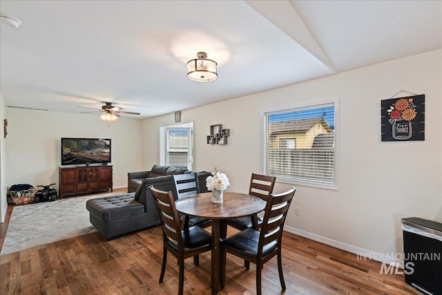 dining space featuring dark wood-type flooring, a ceiling fan, and baseboards