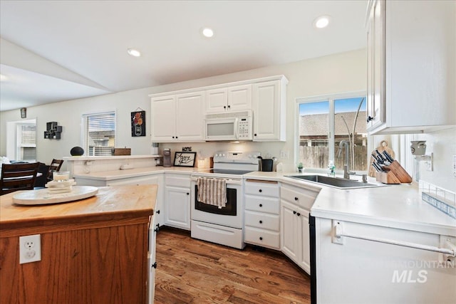 kitchen featuring white appliances, a healthy amount of sunlight, vaulted ceiling, and white cabinets