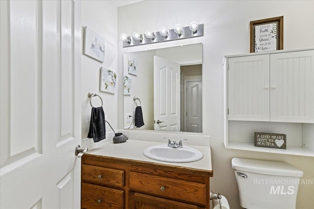 half bath featuring vanity and toilet