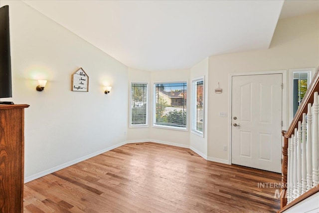 foyer entrance featuring baseboards, wood finished floors, and a wealth of natural light
