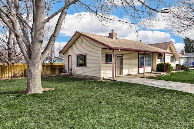 view of front of property with fence, a shingled roof, a chimney, a front lawn, and a patio area