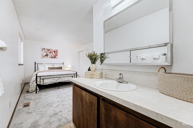 ensuite bathroom featuring vanity, ensuite bath, visible vents, and a textured ceiling