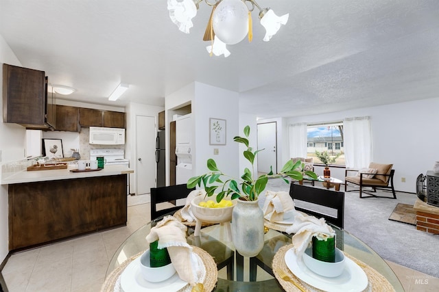 dining space featuring a textured ceiling, light tile patterned floors, light colored carpet, and a chandelier