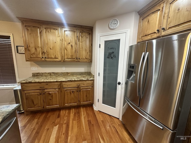 382 N 1020 E, Declo, ID 83323 - kitchen featuring brown cabinets, light stone counters, stainless steel fridge, and wood finished floors
