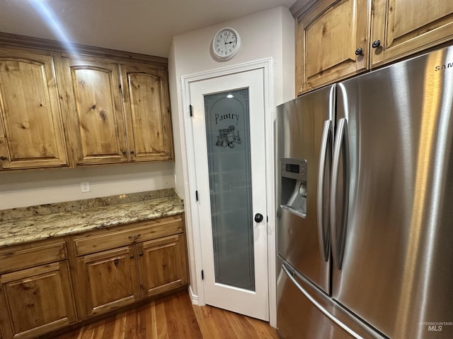 382 N 1020 E, Declo, ID 83323 - kitchen with stainless steel fridge with ice dispenser, light stone counters, dark wood-type flooring, and brown cabinets