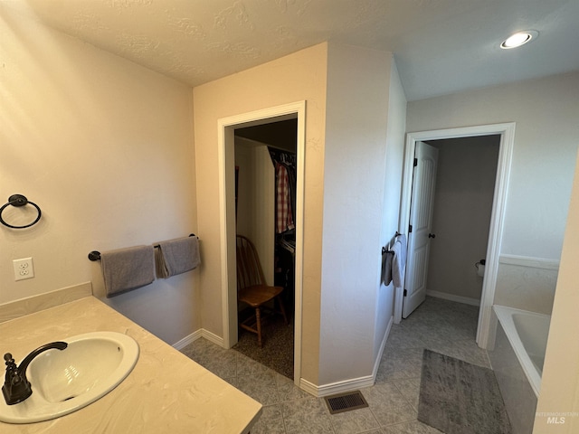 382 N 1020 E, Declo, ID 83323 - bathroom with a sink, a tub to relax in, a textured ceiling, visible vents, and baseboards