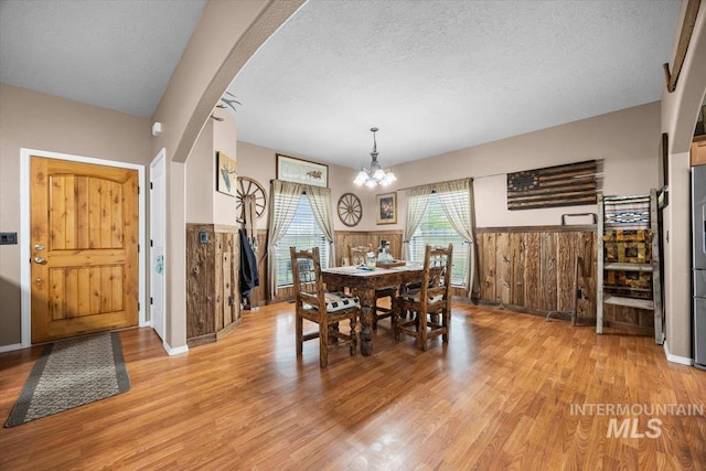 3856 Wood Way, New Plymouth, ID 83655 - dining space featuring an inviting chandelier, wainscoting, light wood finished floors, arched walkways, and a textured ceiling
