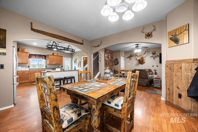 3856 Wood Way, New Plymouth, ID 83655 - dining area with baseboards, arched walkways, light wood-style flooring, and ceiling fan with notable chandelier