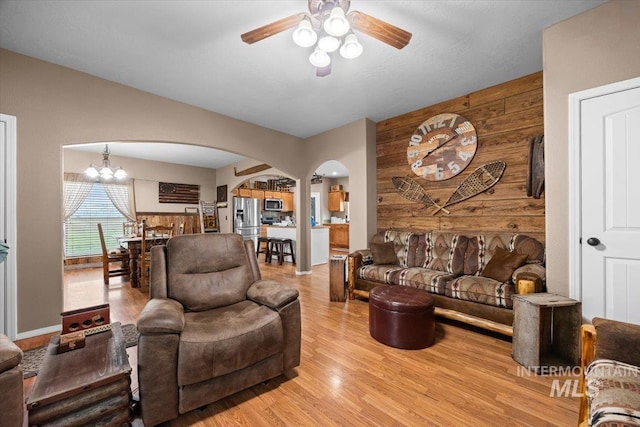 3856 Wood Way, New Plymouth, ID 83655 - living room with light wood-style floors, arched walkways, ceiling fan with notable chandelier, and wooden walls