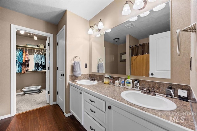 3856 Wood Way, New Plymouth, ID 83655 - full bathroom with visible vents, a sink, a walk in closet, and wood finished floors