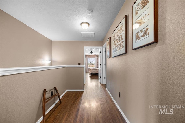 3856 Wood Way, New Plymouth, ID 83655 - hallway featuring a textured wall, a textured ceiling, baseboards, wood finished floors, and visible vents