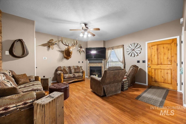 3856 Wood Way, New Plymouth, ID 83655 - living room with a ceiling fan, a textured ceiling, a glass covered fireplace, and light wood-style flooring