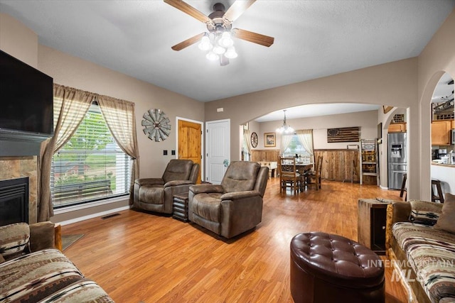 3856 Wood Way, New Plymouth, ID 83655 - living area with arched walkways, light wood-style flooring, ceiling fan with notable chandelier, and a wealth of natural light