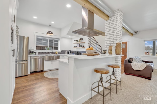 kitchen featuring appliances with stainless steel finishes, a breakfast bar, sink, white cabinets, and kitchen peninsula