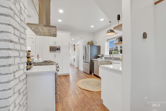 kitchen with appliances with stainless steel finishes, island range hood, decorative light fixtures, and white cabinets