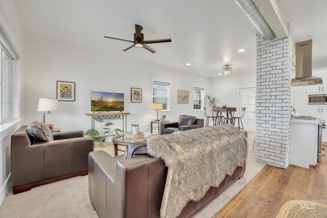 living room featuring decorative columns, ceiling fan, and light hardwood / wood-style flooring