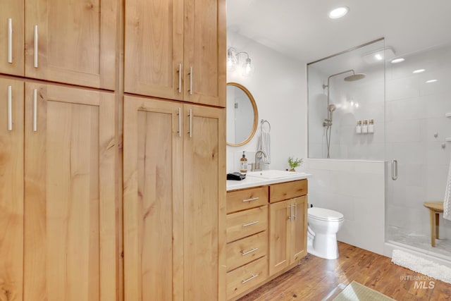 bathroom featuring vanity, hardwood / wood-style flooring, a shower with shower door, and toilet