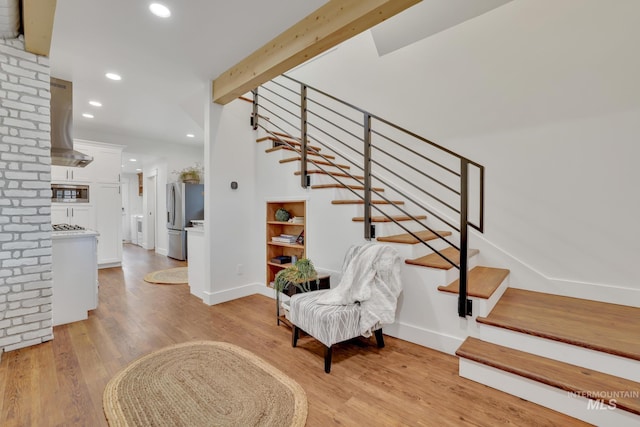 foyer with beamed ceiling and light wood-type flooring