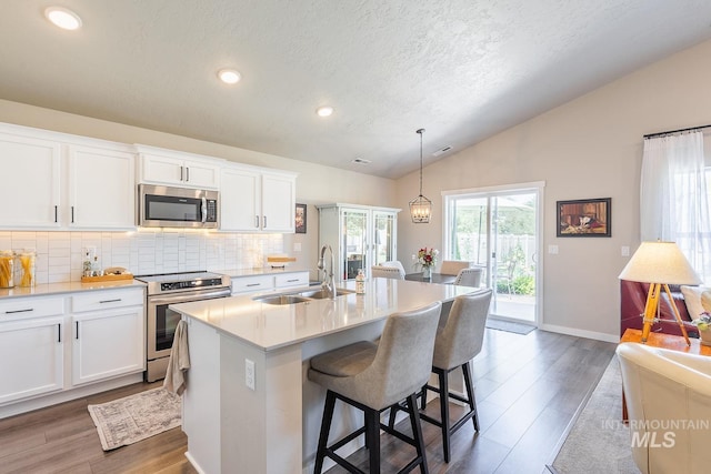 3772 S Walnut Ridge Way, Nampa, ID 83686 - kitchen with appliances with stainless steel finishes, lofted ceiling, tasteful backsplash, light countertops, and a center island with sink