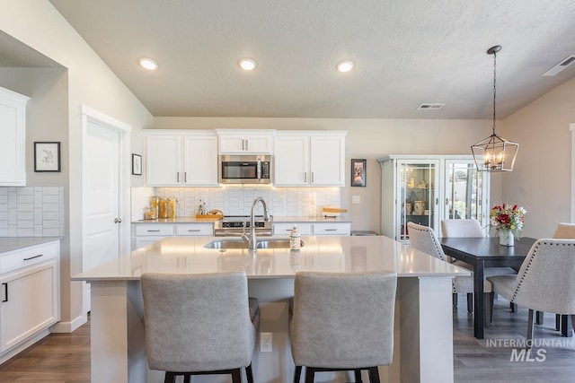 3772 S Walnut Ridge Way, Nampa, ID 83686 - kitchen with stainless steel microwave, dark wood-style floors, backsplash, a chandelier, and recessed lighting