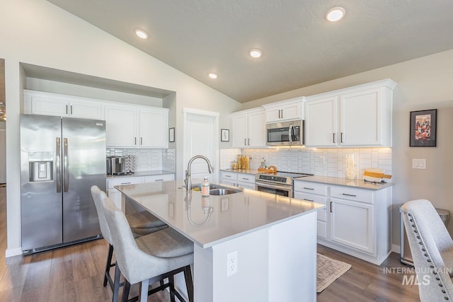 3772 S Walnut Ridge Way, Nampa, ID 83686 - kitchen with stainless steel appliances, dark wood-type flooring, vaulted ceiling, a center island with sink, and a kitchen bar