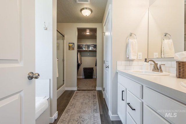 3772 S Walnut Ridge Way, Nampa, ID 83686 - bathroom with a shower stall, vanity, wood finished floors, a textured ceiling, and a spacious closet