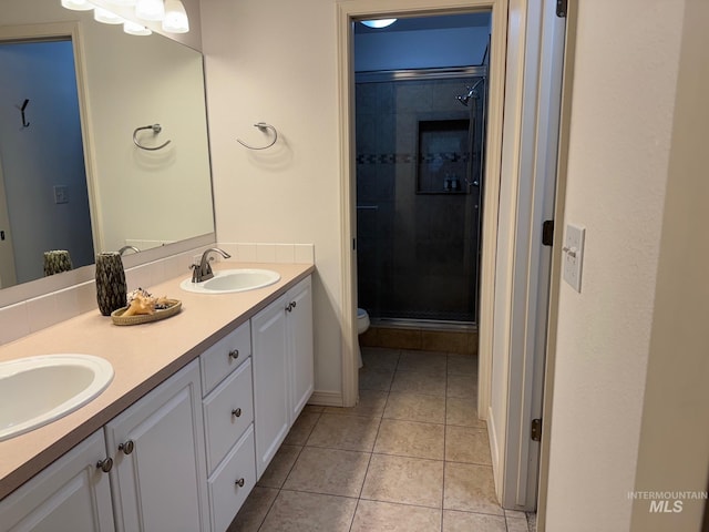 full bathroom featuring toilet, a stall shower, a sink, tile patterned flooring, and double vanity