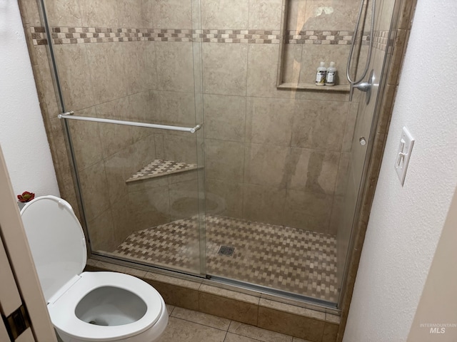 full bathroom featuring tile patterned floors, toilet, and a shower stall