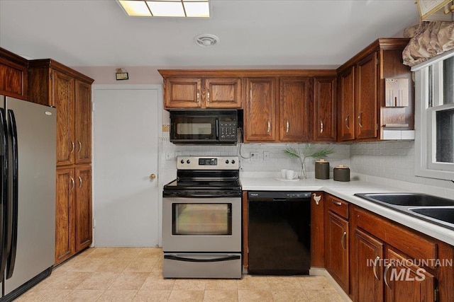 kitchen featuring black appliances, light countertops, tasteful backsplash, and a sink