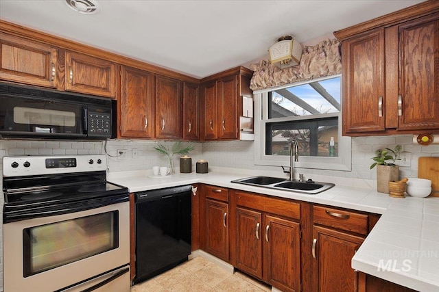 kitchen featuring brown cabinetry, backsplash, black appliances, and a sink