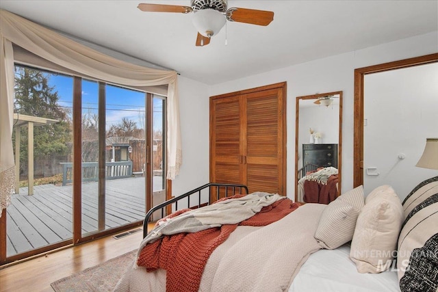 bedroom with wood finished floors, visible vents, ceiling fan, a closet, and access to outside