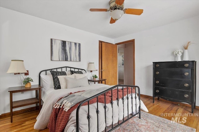 bedroom featuring ceiling fan, baseboards, and wood finished floors