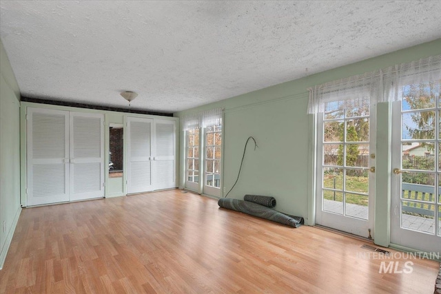 unfurnished bedroom with visible vents, wood finished floors, a textured ceiling, and access to exterior