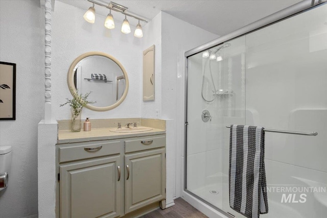 full bathroom with a shower stall, vanity, toilet, and wood finished floors