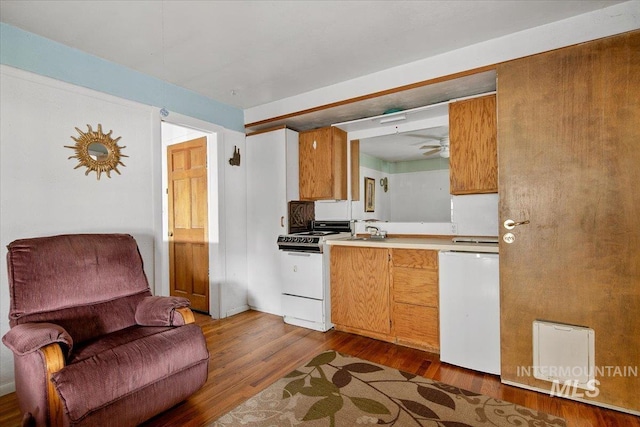 kitchen with dishwashing machine, white range with gas stovetop, dark wood-style flooring, light countertops, and brown cabinets