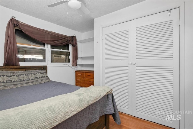 bedroom with ceiling fan, a closet, a textured ceiling, and wood finished floors