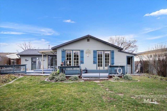 view of front of home with a deck, a front yard, and fence