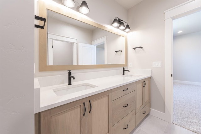 full bath with double vanity, tile patterned flooring, baseboards, and a sink