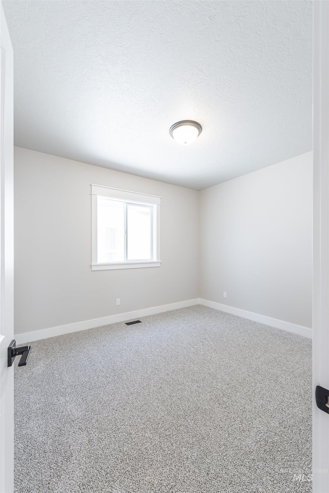 carpeted empty room with baseboards, visible vents, and a textured ceiling